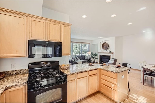 kitchen featuring open floor plan, black appliances, and light brown cabinetry