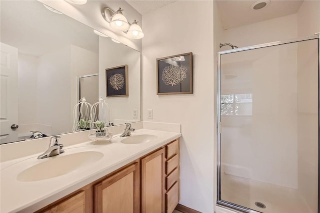 full bathroom featuring double vanity, a shower stall, and a sink