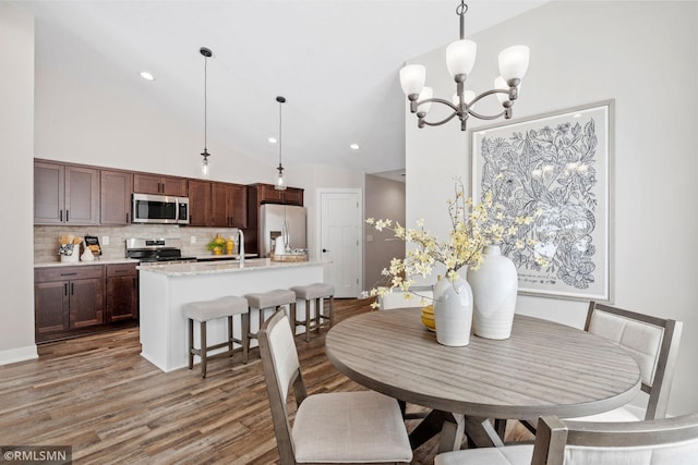 dining space with a notable chandelier, high vaulted ceiling, light wood finished floors, and recessed lighting