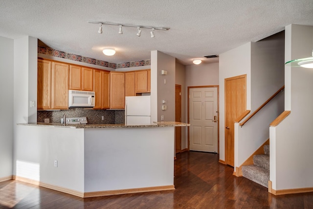 kitchen with white appliances, dark wood finished floors, a peninsula, and backsplash