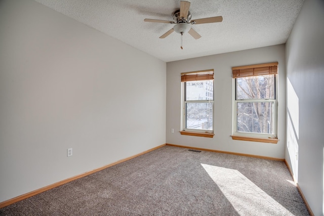 spare room with carpet floors, baseboards, visible vents, and a textured ceiling