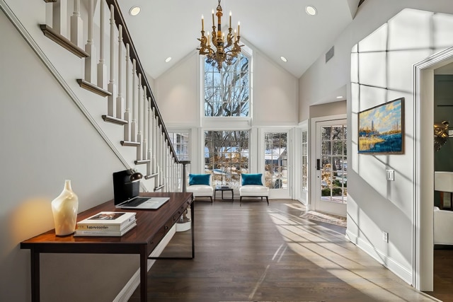 foyer with a chandelier, high vaulted ceiling, wood finished floors, visible vents, and stairway