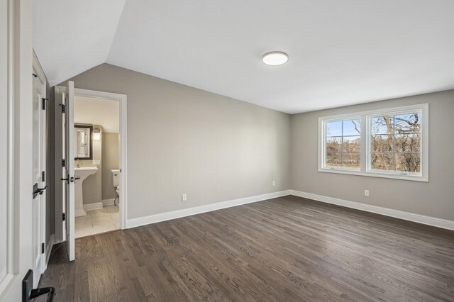 10 Saint Albans Rd E, Hopkins, MN 55305 - unfurnished bedroom with dark wood-style flooring, vaulted ceiling, ensuite bathroom, and baseboards