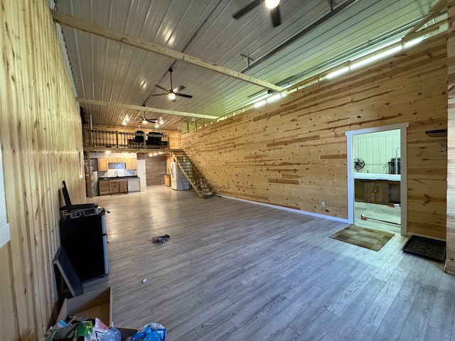 interior space featuring ceiling fan, wooden walls, and wood finished floors