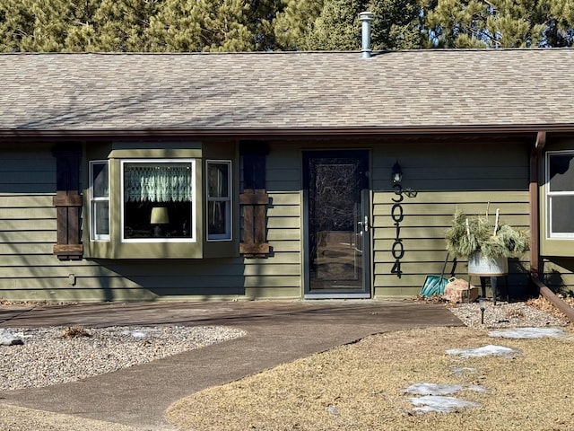 doorway to property with roof with shingles