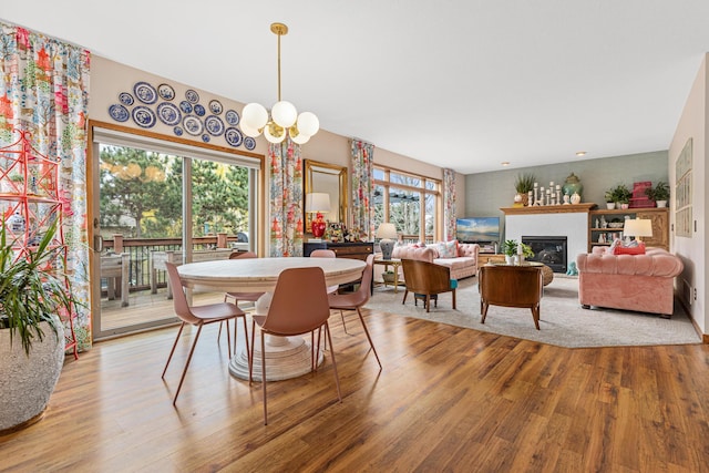 dining room with a glass covered fireplace, light wood-type flooring, and a notable chandelier