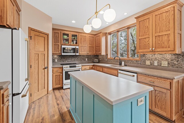 kitchen with white appliances, a sink, light wood-style flooring, and tasteful backsplash