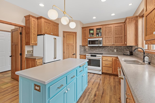 kitchen featuring white appliances, a center island, a sink, backsplash, and blue cabinetry