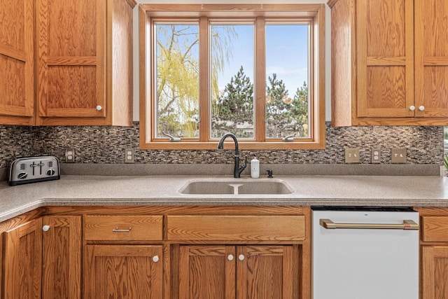kitchen featuring backsplash, light countertops, a sink, and dishwasher