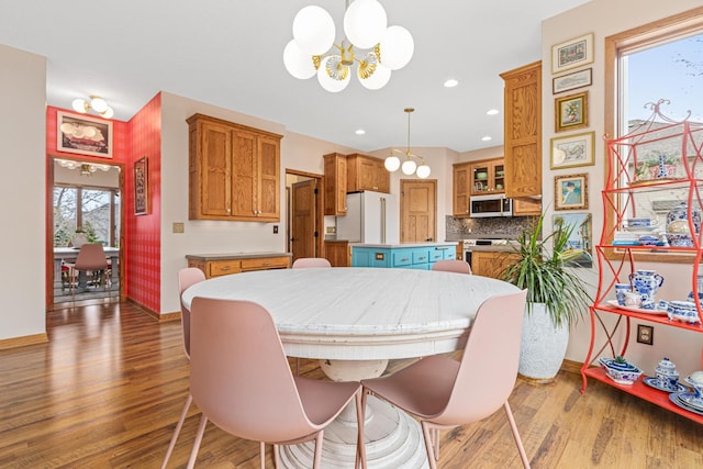 dining space featuring baseboards, a notable chandelier, and wood finished floors