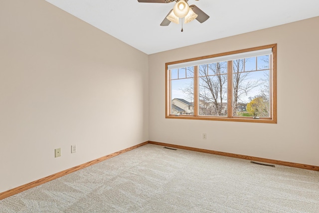 empty room featuring baseboards, a ceiling fan, light colored carpet, and visible vents