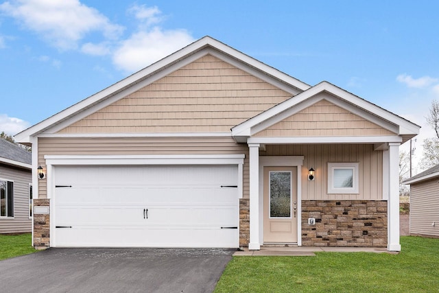 view of front of house featuring an attached garage, stone siding, a front lawn, and aphalt driveway