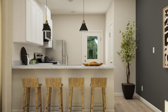 kitchen featuring stainless steel electric range oven, light countertops, freestanding refrigerator, light wood-style floors, and white cabinetry