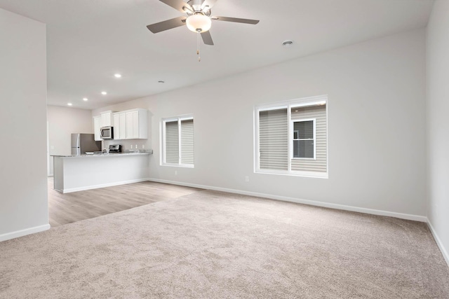 unfurnished living room with recessed lighting, baseboards, light carpet, and ceiling fan