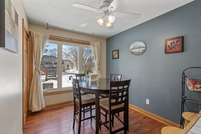 dining room with a textured ceiling, baseboards, and wood finished floors