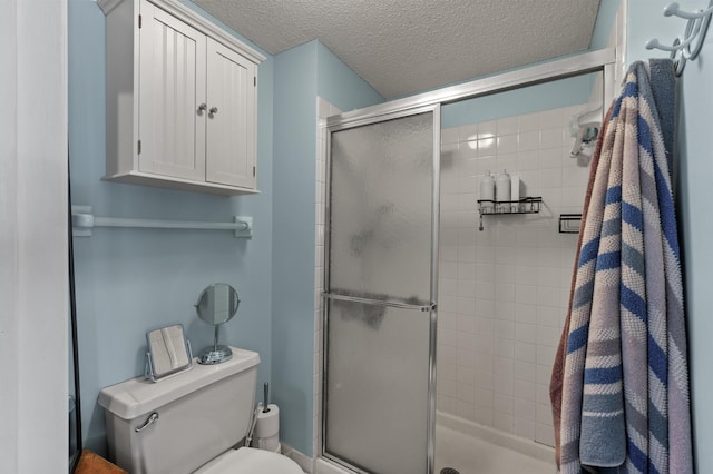 bathroom with a shower stall, toilet, and a textured ceiling