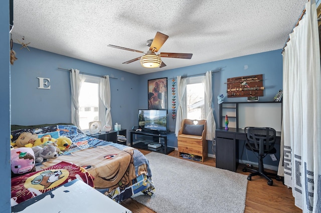 bedroom featuring baseboards, a textured ceiling, wood finished floors, and a ceiling fan