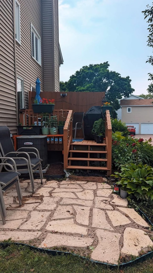 view of patio / terrace with a deck, central AC unit, and fence