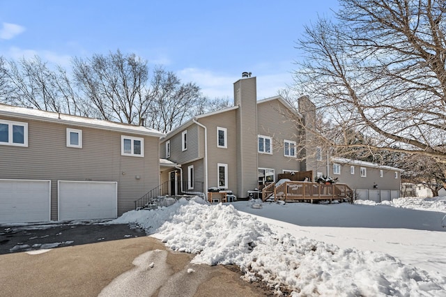 snow covered house featuring a wooden deck and a garage