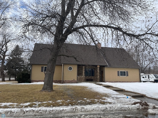 view of front facade featuring roof with shingles and a chimney