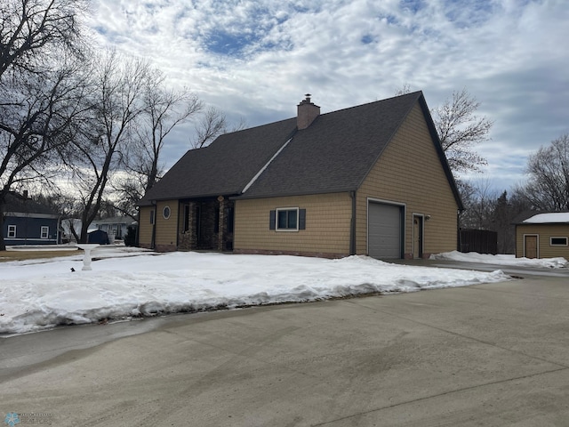 view of front of house with a garage, a chimney, and a shingled roof