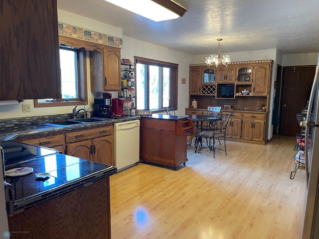 kitchen featuring a sink, dark countertops, a peninsula, dishwasher, and a chandelier