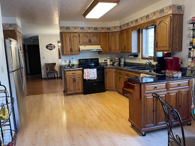 kitchen with dark countertops, freestanding refrigerator, exhaust hood, black / electric stove, and a sink