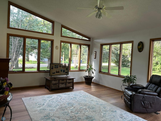 sunroom / solarium featuring plenty of natural light, ceiling fan, and lofted ceiling