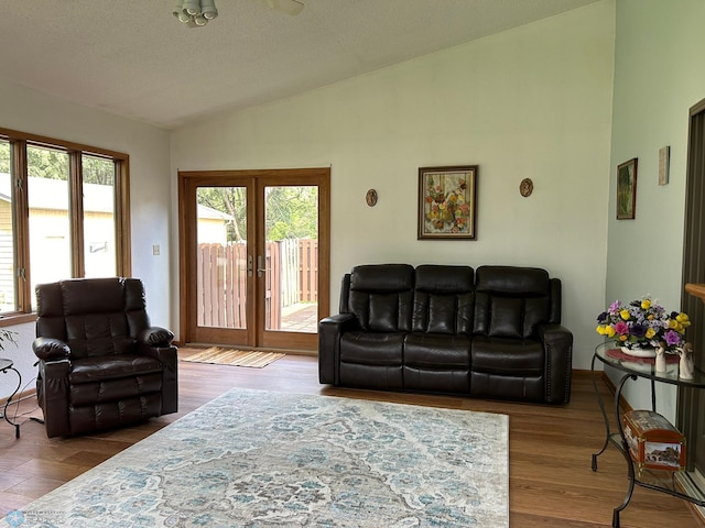 living area featuring vaulted ceiling, wood finished floors, and french doors