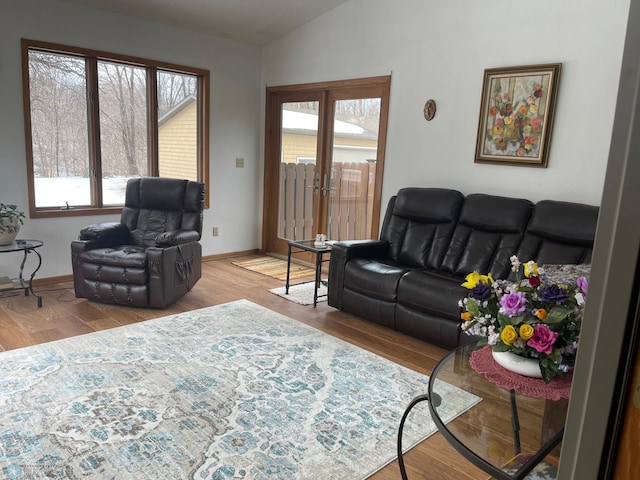 living room featuring french doors, lofted ceiling, baseboards, and wood finished floors