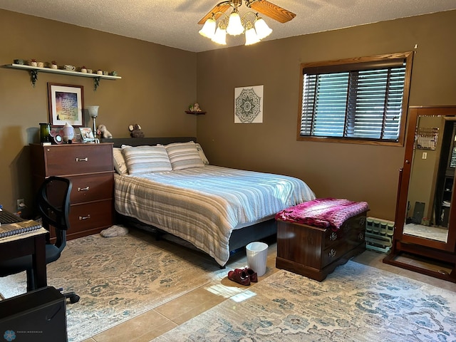 bedroom with a textured ceiling, ceiling fan, and tile patterned flooring