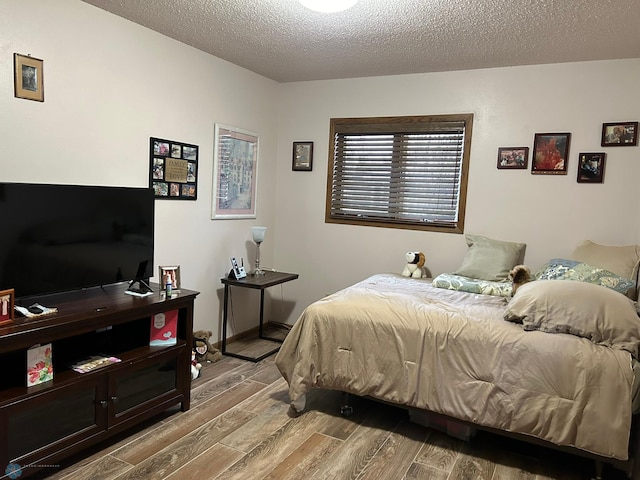 bedroom with a textured ceiling, baseboards, and wood finished floors