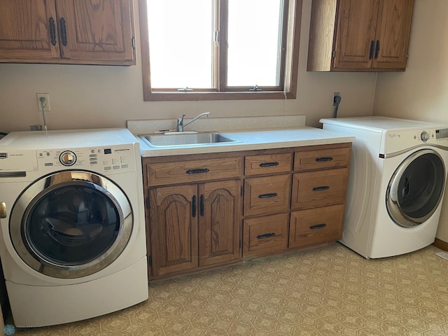 clothes washing area featuring washing machine and dryer, cabinet space, light floors, and a sink