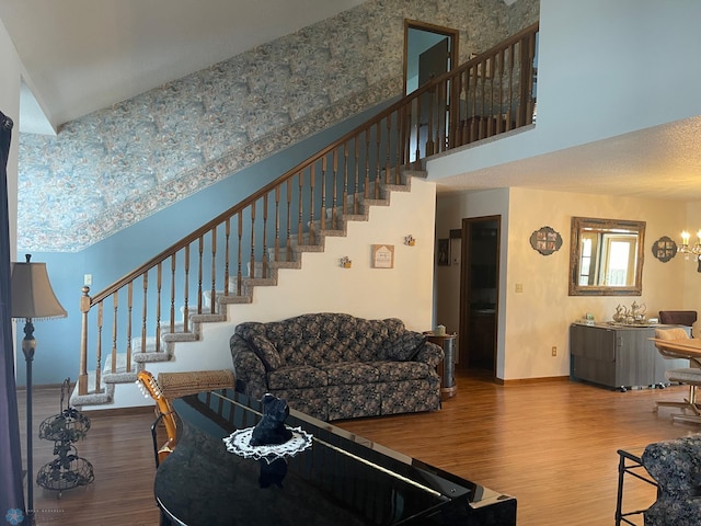 living room featuring stairway, baseboards, a high ceiling, and wood finished floors