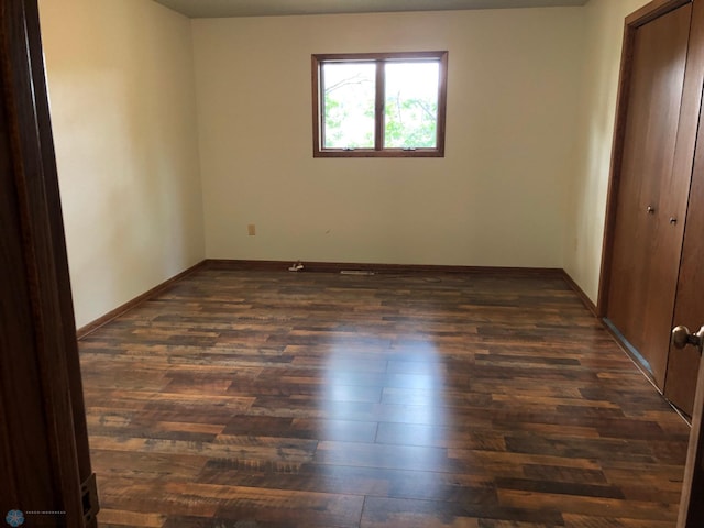 unfurnished bedroom with dark wood finished floors, a closet, and baseboards