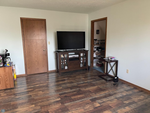 living room featuring baseboards, a textured ceiling, and wood finished floors