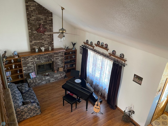 living area with wood finished floors, lofted ceiling, ceiling fan, a textured ceiling, and a brick fireplace