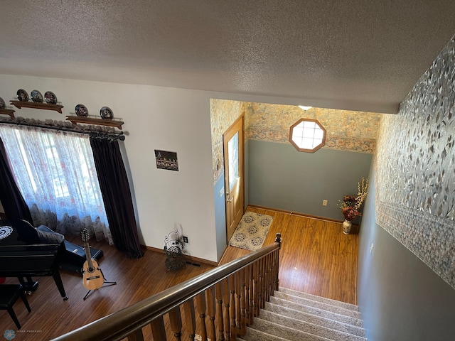 stairway featuring baseboards, a textured ceiling, and wood finished floors