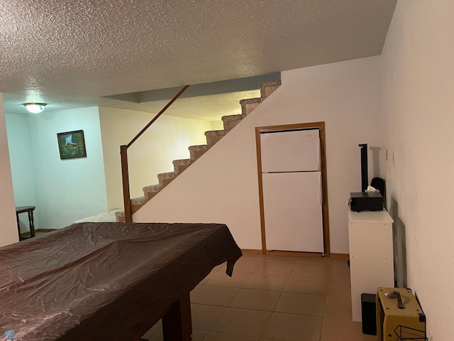 game room featuring tile patterned flooring and a textured ceiling