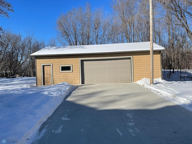 snow covered garage featuring a garage