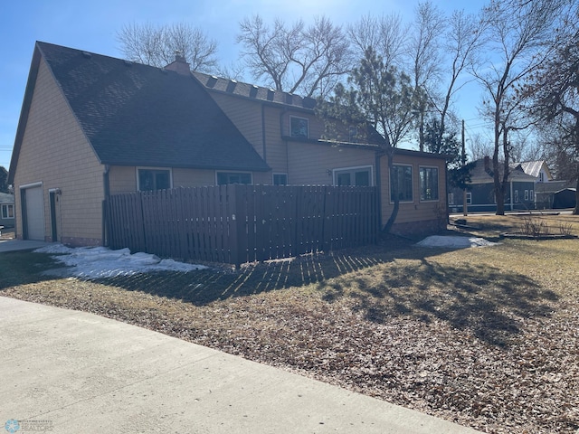 rear view of property featuring a fenced front yard, an attached garage, and a chimney