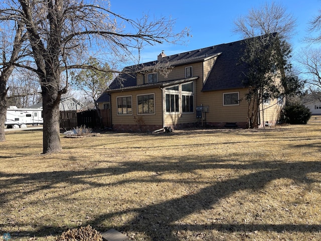 back of property with a shingled roof, a yard, fence, and a chimney