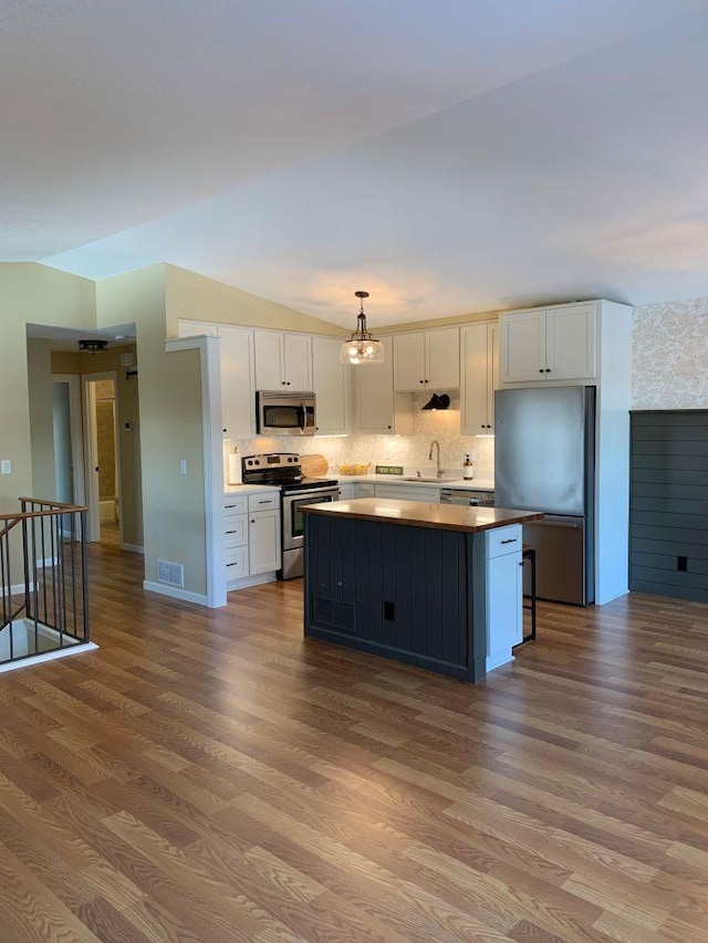 kitchen featuring lofted ceiling, white cabinetry, stainless steel appliances, and a center island