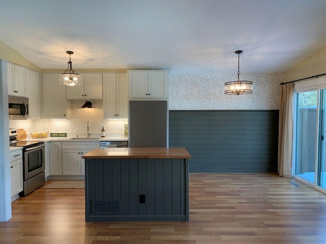 kitchen with wallpapered walls, white cabinetry, appliances with stainless steel finishes, and a sink