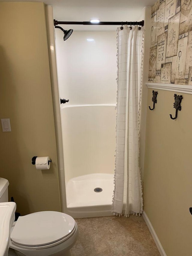 full bathroom with baseboards, a shower stall, and toilet