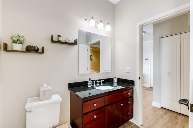 bathroom with toilet, vanity, and wood finished floors