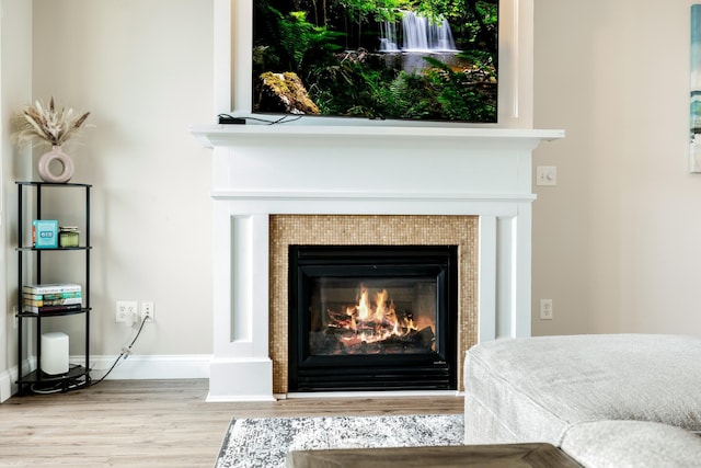 interior details with baseboards, wood finished floors, and a tiled fireplace