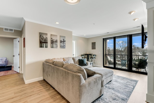 living area featuring visible vents, light wood-style flooring, baseboards, and ornamental molding