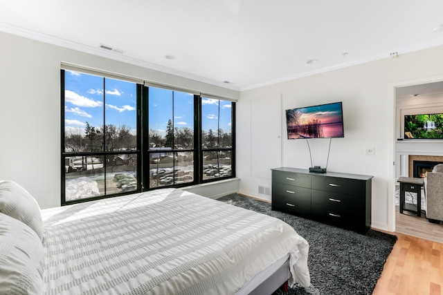 bedroom featuring visible vents, multiple windows, crown molding, and light wood-style floors