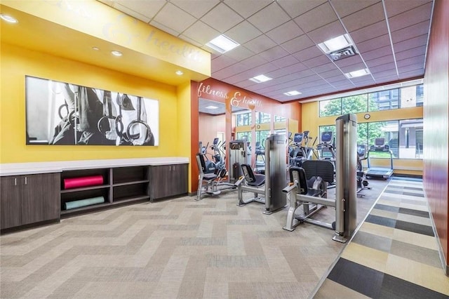 workout area featuring visible vents, light colored carpet, and a drop ceiling